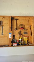 Wide view showing hammers, saw, scraper, lubricant cans, and some files in wood storage compartment
