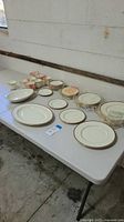 Wide view of all china items on table showing arrangement of plates, cups, saucers, platter, and bowl