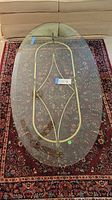 Full view from above of the oval glass top coffee table showing clear glass and brass frame.