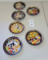 Full view of the 6 decorative Rosenthal plates arranged on a table showing colorful Aladdin themed artwork and gold accents.