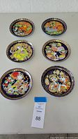 Set of six colorful Rosenthal Aladdin Special Edition collector's plates with artistic gold borders, displayed on a white table.