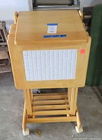 Overall view of tray tables nested in matching wooden stand showing four trays with white tile inlays and stand with wheels.