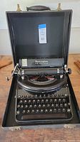 Full view of typewriter inside black carrying case with Remington Noiseless brand visible