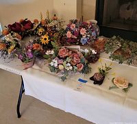 Overall view of assorted artificial wreaths and floral decor items on table showing multiple colors and flower types
