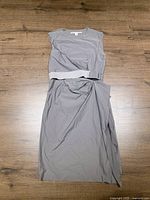 Full view of the grey dress laid flat showing its belted waist and sleeveless design.