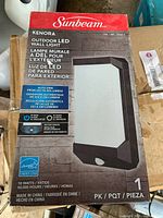 Photo of new in box Sunbeam Kenora outdoor LED wall light packaging showing brand, model, features, and specifications.