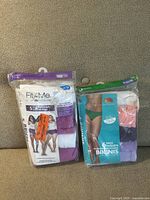 Photo of two sealed packs of ladies' underwear on carpet. One pack Fit Me 3 pairs briefs, the other Secret Treasures 6 pack bikini briefs in assorted colors.
