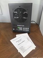 Black Breathe Fresh ozone air purifier with control panel and owner's manual on wooden surface