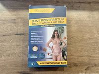 Front view of the product box showing brand, model, and features of the postpartum belly wrap and hip belt set.