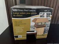 Boxed solar fence post lantern showing product image and description, listing features such as easy installation, solar power, polycrystal solar panel, and LED light. Price label on box shows $23.99.