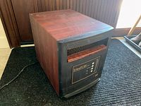 Side angle view showing the wood finish, black edges, and paint splatter on top of the EdenPURE space heater.