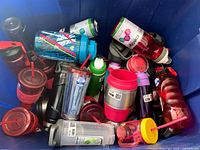 Multiple assorted drink holders including tumblers and bottles piled together in a bin.