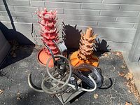Full view of two orange bottle drying stands and wine transfer pump with hoses outside near concrete wall.
