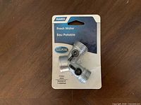 Photo of a new Camco Y-Valve in packaging, showing the silver Y-shaped valve with control knobs and threaded ends.