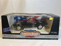 Front view of boxed 1967 Corvette L-71 die cast metal model in black with red interior inside original American Muscle packaging with visible 25th Year Anniversary badge and minor box wear.