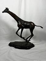 Side view of the hollow brass giraffe sculpture on the wooden base
