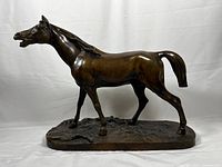 Full side view of bronze horse on oval base