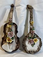 Pair of antique Capodimonte porcelain wall hangings shaped as a violin and mandolin with painted and applied flowers, brown and white base.