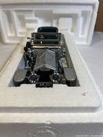 Front close-up of 1907 Rolls Royce Silver Ghost model car in white foam packaging, showing silver body and headlights.