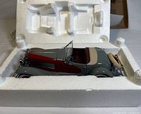 Side view of the grey and red 1935 Duesenberg SSJ Sportster diecast model car in original white Styrofoam packaging.