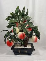 Front view of the vintage jade bonsai tree featuring eight peaches nestled among green leaves in a black rectangular planter with gold Chinese characters