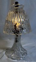 Front view of Princess House clear crystal mini table lamp illuminated, showing floral and leaf pattern etched into the glass shade and base.