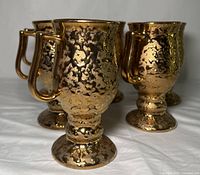 Six vintage Bel-Terr China coffee mugs with a textured dipping of 22K gold in an abstract pattern, showing exterior, pedestal footed base, and gold-coated handle.