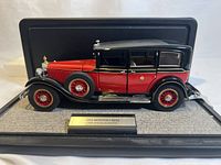 Side profile of the 1:24 scale die-cast model showing red and black two-tone paint with chrome detailing, displayed on a base with nameplate.