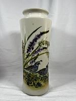 Front view of tall white porcelain vase with detailed painted California quail and purple botanical design