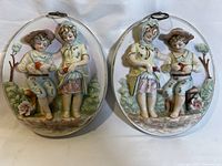 Two oval Arnart ceramic plaques displayed side by side, showing children harvesting apples, featuring raised 3D detail and pastel colors.