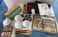 Photo showing white ceramic rice bowls, assorted chopstick sets, bamboo mats, new towel package, and woven mats with Japanese scenic designs