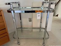 Front view of chrome frame drink cart showing two glass shelves and casters