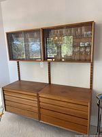 Overall view of two upper glass-front cabinets mounted above two lower drawer cabinets on wall rails