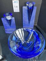 Two blue glass Ice Age candle holders, one 8 inches tall and one 11 inches tall, with characteristic triangular conical candle cups and rectangular backplates on a black background.