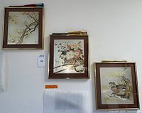 Three framed Chokin art prints hung on wall with one folding fan resting on top of each frame. Gold-tone frames, art size approximately 12.5 x 14 inches. The fans are unrelated to art.
