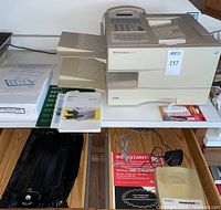 Pitney Bowes 9910 postage meter with manuals, spare cartridge, and documentation on table, commanding presence of original materials and device condition visible.