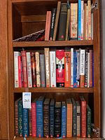 Three-shelf wooden bookcase showing modern cloth and paperbacks on middle and top shelves