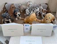 Photo of all eight Lenox puppy dog figurines together in a box along with some Lenox paperwork.