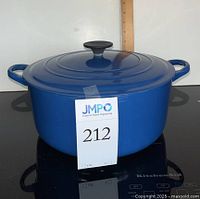 Front view of blue enameled cast iron Dutch oven with lid on cooktop