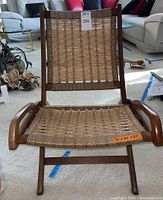 Front view of folding chair showing woven rope seat and back on wooden frame