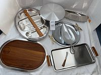 Photo showing all 7 metal platters and serving pieces in the lot, including a swiveling cake pedestal, divided sectional tray, leaf tray, and wooden trays.