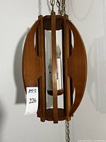 Overall view of wooden pierced oval pendant light hanging from brass chain