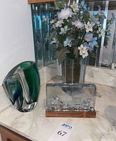 Photo of all three glass items together showing the green Kosta Boda vase, clear Strömbergshyttan vase, and scenic glass piece on wooden base