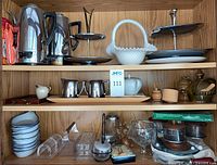 Shelf showing variety of vintage serving and kitchen items including milk glass basket, serving trays, metal and glass pieces