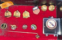 Assorted lapel pins, cufflinks and tie clip on red felt