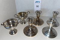 Overview of two-piece sugar and creamer set at left with two pairs of candlesticks at right