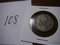 Photo of the 1942 Canadian quarter in protective 2x2 cardboard holder, showing the reverse side with caribou design and the year 1942 visible