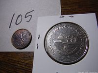 Photo showing the silver-colored 1978 Parry Sound $1 coin in a white holder and a copper Canadian penny for scale.