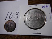 1979 Canadian silver dollar coin front side featuring a canoe scene and a Canadian one cent coin for size comparison.