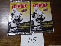 Two unopened 2008-2009 Upper Deck Victory hockey card packs on wood surface with a small numbered paper.